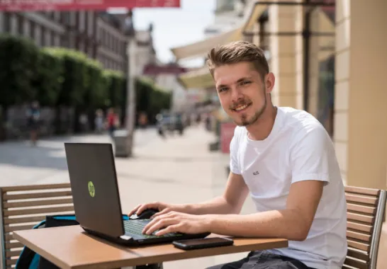 Ein Mann sitzt vor seinem Laptop im Café.