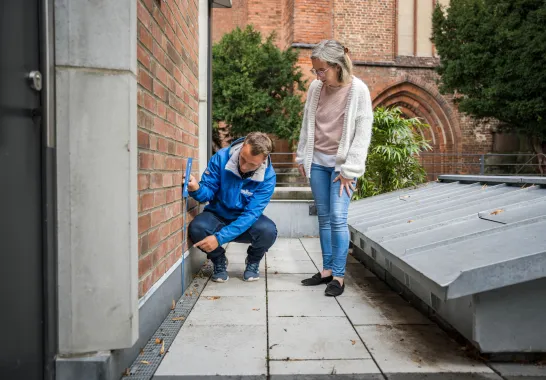 Ein Mitarbeiter der Stadtwerke Schwerin misst mit einem Zollstock an der Hauswand.