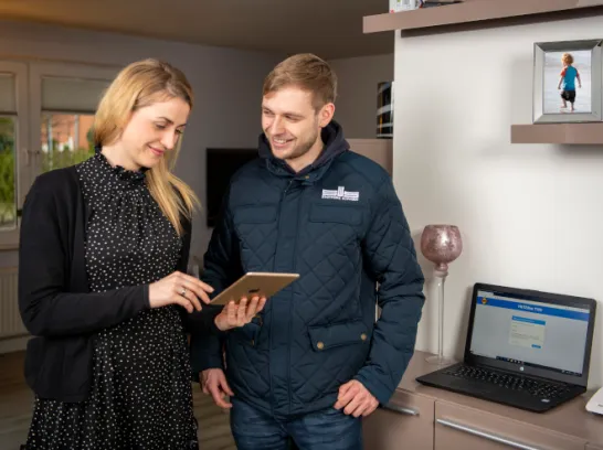 Ein Servicetechniker unterstützt eine Kundin bei der Interneteinrichtung auf ihren Geräten.