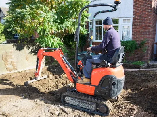 Ein Mann arbeitet mit einem Mini-Bagger.