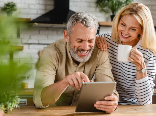 Pärchen steht in der Küche und schaut sich etwas auf dem Tablet an