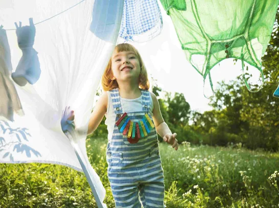 Ein Kleinkind läuft unter einer Wäscheleine entlang.