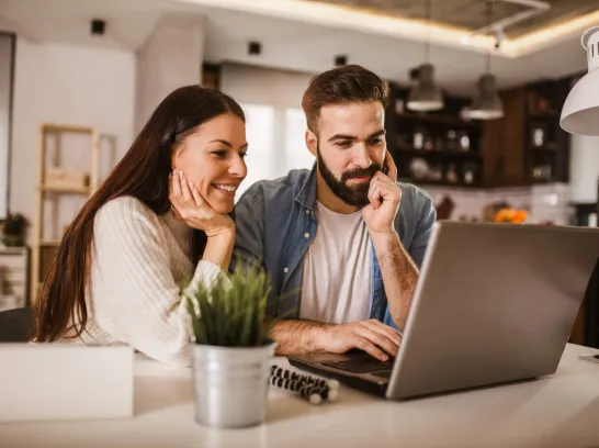 Ein glückliches Paar schaut zusammen auf ein Notebook.