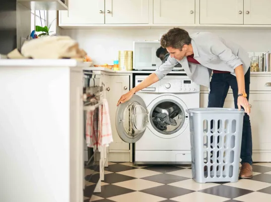 Ein Mann wäscht seine Wäsche in der Waschmaschine.