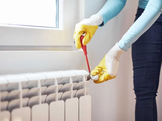 Eine Frau entlüftet ihre Heizung.