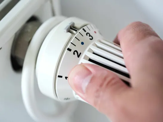 Eine Hand stellt die Heizung auf mittlere Stufe.