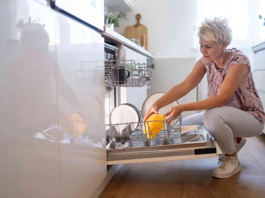 Eine Frau bestückt ihren Geschirrspüler.