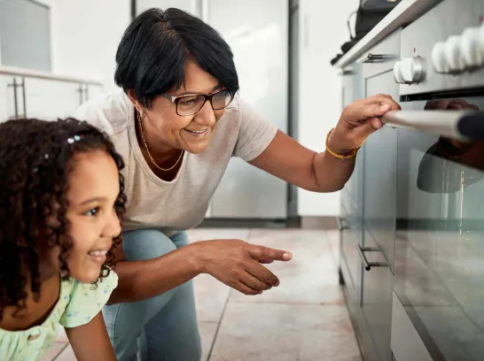 Eine Frau schaut mit ihrer Enkelin in den Ofen.