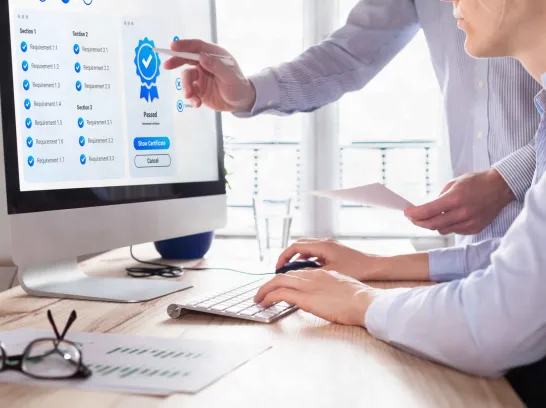 Kollegen schauen sich auf einem Bildschirm eine Zertifizierung an.