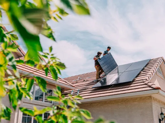 Zwei Männer installieren Solarmodule auf einem Dach.
