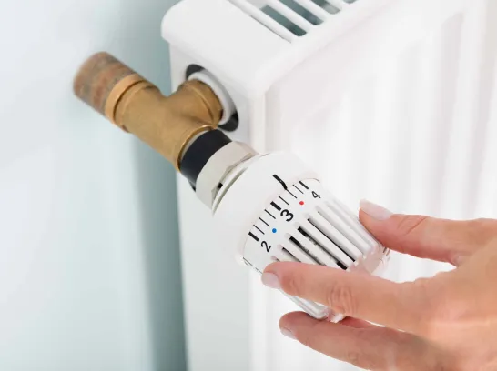 Eine Frau dreht am Heizungsthermostat.
