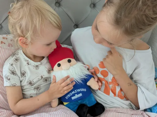 Zwei Mädchen halten gemeinsam einen Kuscheltierzwerg.