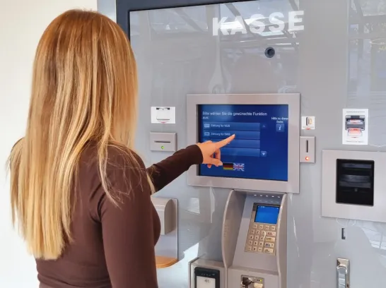 Eine junge Frau tippt auf den Bildschirm des Kassenautomaten im Kundencenter der Stadtwerke.