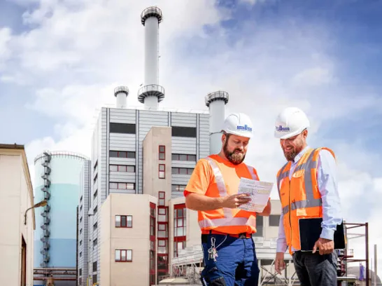 Zwei Stadtwerkemitarbeiter stehen vor einem Kraftwerk