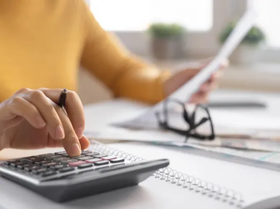 Eine Frau tippt auf einem Taschenrechner.