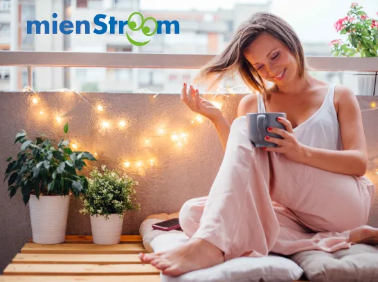 Eine junge Frau sitzt glücklich auf dem Balkon.