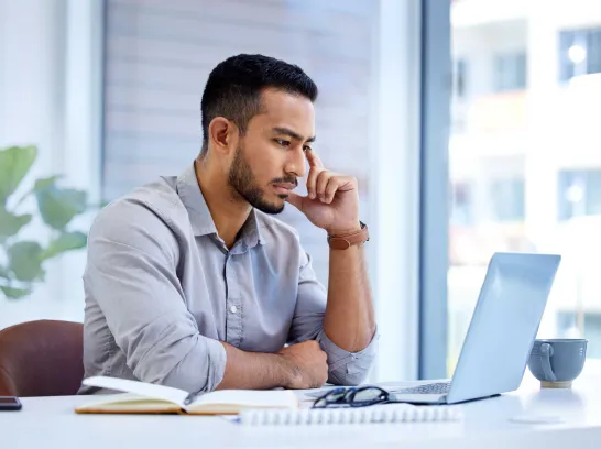 Ein Mann schaut besorgt auf einen Laptop.