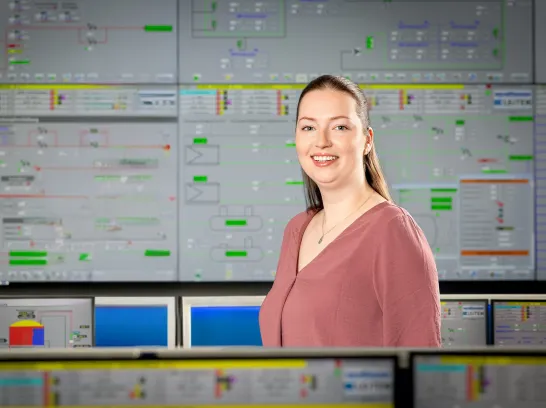 Eine Mitarbeiterin steht vor einem großflächigen Monitor in der Leitwarte.