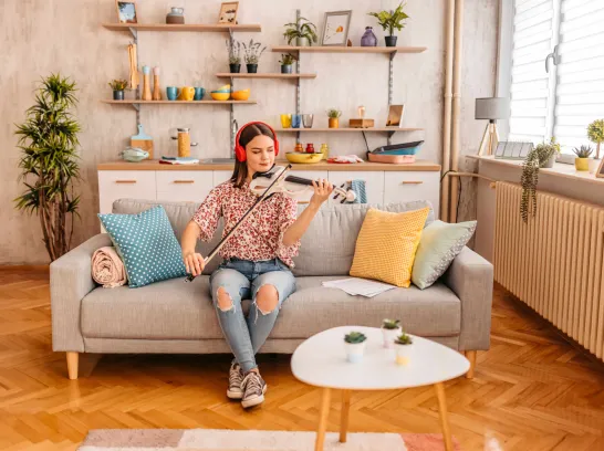 Eine Frau sitzt auf dem Sofa und spielt Geige.