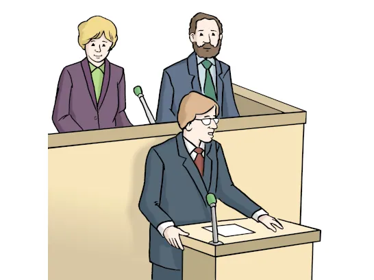 Drei Politiker tragen Anzüge. Einer spricht am Rednerpult mit Mikrofon. Die anderen zwei stehen dahinter mit einem Mikrofon.