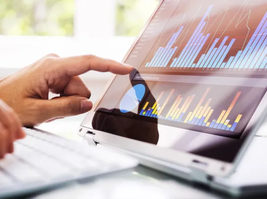 Eine Person tippt auf einem Tablet, das Diagramme zeigt.