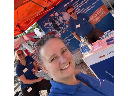 Drei Mitarbeitende der Stadtwerke in einem orangen Pavillon