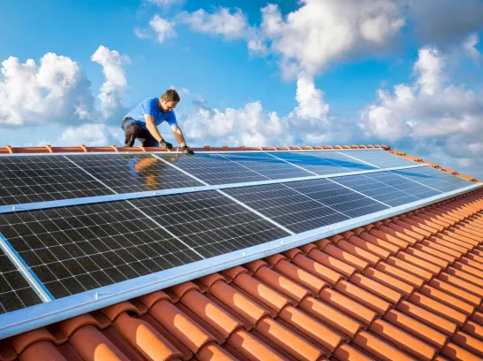 Ein Handwerker installiert eine Photovoltaikanlage auf einem Dach.
