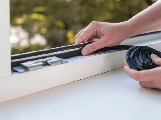 Jemand dichtet ein Fenster ab.