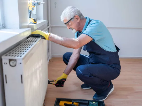 Ein Handwerker wartet eine Heizung, um Energie zu sparen.