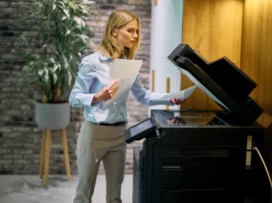 Eine Mitarbeiterin kopiert Unterlagen am Drucker.