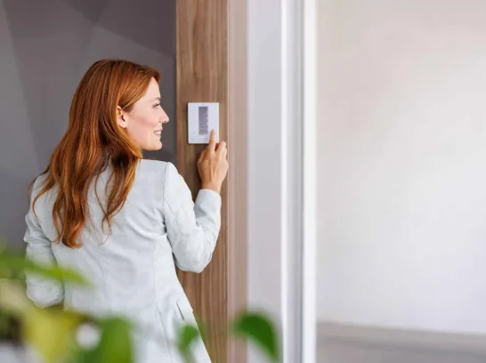 Eine Frau stellt ein Thermostat ein, um Energie zu sparen.