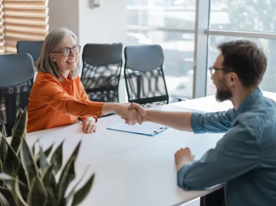 Eine Frau und ein Mann geben sich an einem Tisch die Hand