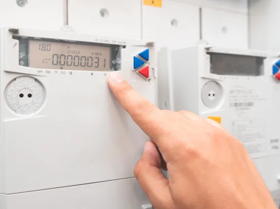 Eine Person liest den Zählerstand vom Display eines digitalen Zählers ab