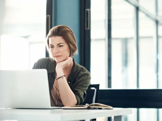 Junge Frau schaut im Büro auf den Bildschirm eines Notebooks