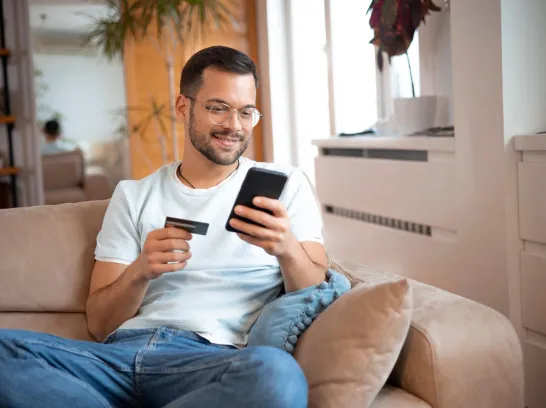 Ein Mann gibt Daten seiner Bankkarte auf seinem Handy ein