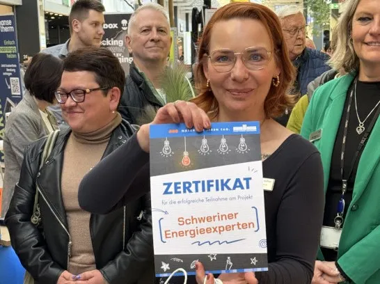 Eine Mitarbeiterin der Stadtwerke hält ein Zertifikat in die Kamera