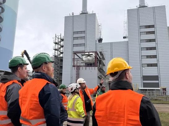 Eine Besuchergruppe steht vor dem charakteristischen Heizkraftwerk in Schwerin Süd.